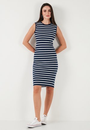 Navy blue and white striped midi dress with a fitted silhouette, sleeveless design, and smooth texture. Worn with white sneakers.