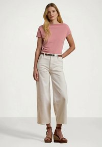 Light pink short-sleeve top paired with ivory wide-leg trousers and brown wedge sandals. The outfit features a silver belt detail.