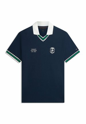 Marineblå polo med hvid krave, grønne og hvide striber på ærmer og krave, Tommy Hilfiger-logo og tekst på brystet.