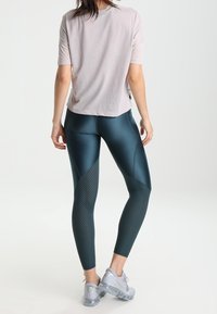 Top deportivo de manga corta en rosa claro con un patrón texturizado, combinado con leggins en azul oscuro que presentan detalles punteados y un acabado brillante.