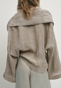 Linnen overhemd met lange mouwen in een lichtbeige kleur, met een gestructureerd, gekreukt ontwerp en een brede, gevouwen kraag aan de achterkant.