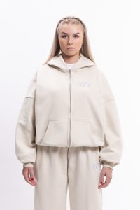 Béžová mikina na zips s veľkými vreckami, voľný strih a vyšívaný kvetinový dizajn na hrudi. Štruktúrovaná tkanina a kapucňa.