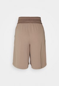 Bruine sportshorts met een gestructureerde elastische tailleband, die een losse pasvorm en een gladde stofstructuur bieden. Geen zakken zichtbaar aan de achterkant.