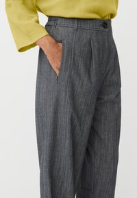 Szare, teksturowane spodnie o dopasowanym kroju, z przodu plisowane, z bocznymi kieszeniami i brązowym guzikiem przy pasku w talii.