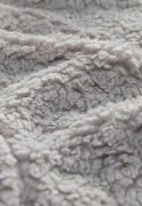 Grå, tekstureret plaid med en fluffy, blød overflade, der har et bølget mønster; tykt og hyggeligt materiale designet til varme.