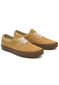 Baskets en daim couleur noisette avec des lacets blancs, conçues avec un profil bas, un bout arrondi et une semelle extérieure en caoutchouc brun foncé. Détails comprenant un patch logo.