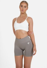 Sive kratke športne hlače z visokim pasom in belim logotipom, v kombinaciji z belim krojenim topom. Gladek, elastičen material z oprijetim dizajnom.