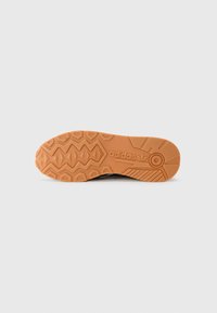 Talpa de pantof Adidas din cauciuc portocaliu cu un model texturat ce include forme geometrice și logo-ul Adidas embosat aproape de călcâi.