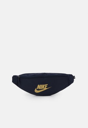 Granatowa nerka Nike z złotym logo, prostokątny kształt, główna komora zamykana na zamek oraz regulowane boczne paski na jednolitym tle.