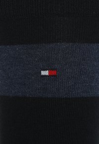 Mörkblå och svarta randiga strumpor gjorda av stickat material, med en liten röd, vit och blå logga på sidan.