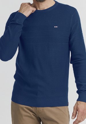 Navy blue knit sweater with textured upper, ribbed cuffs and hem. Features horizontal stripes and a small logo on the chest.
