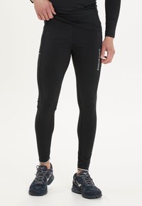 Zwarte sportlegging met een slim fit, gemaakt van vochtregulerende stof, met zijzakken en witte merklogo-accenten.