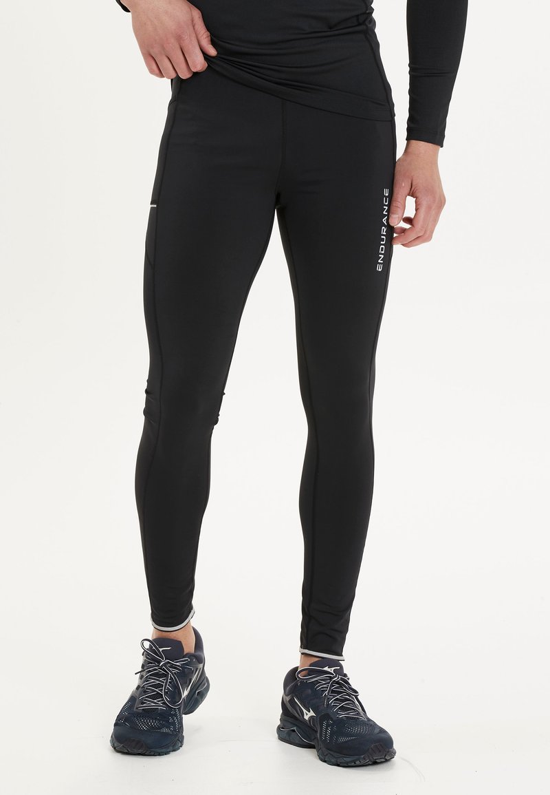 Svarta atletiska tights med slim fit, tillverkade av fukttransporterande material, med sidfickor och vita varumärkeslogotypdetaljer.