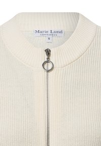 Cremfarbene gestrickte Jacke mit einem gerippten Kragen, Frontreißverschluss und einem großen Metall-Zugring. Mit einem Etikett mit "Marie Lund" Branding.