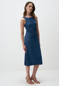 Abito senza maniche blu navy con dettaglio arricciato in vita, silhouette a trapezio, texture liscia e orlo fino al ginocchio. Adatto per varie occasioni.