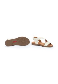 Sandalias de cuero blanco con un diseño de tiras traseras, dos correas anchas en la parte delantera y una suela de goma marrón texturizada.