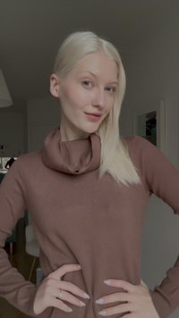 Pruun krae-sweater kitsase disainiga, soonilise tekstuuri ja pikkade varrukatega. Mudel poseerib käed puusadel, näidates rõivast.