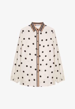Weiße Bluse mit schwarzen Polka-Dots, vorderer Knopfleiste und braun gestreiftem Kragen. Lange, leicht ballonförmige Ärmel. Glatte Stoffstruktur.