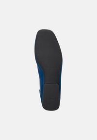 Sole di scarpa blu con gomma nera texturizzata, tacco leggermente rialzato e bordi lisci. Presenta un design minimale senza motivi visibili o hardware.