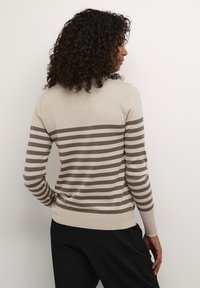 Maglione beige con strisce orizzontali marroni, maniche lunghe e orlo aderente. Il materiale sembra morbido con una consistenza liscia.