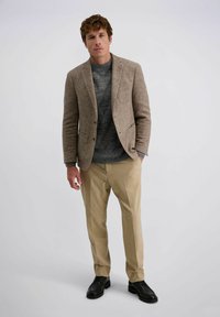 Braunes Hahnentrittmuster-Blazer, grauer Pullover, beigefarbene Hose, schwarze Schuhe. Der Blazer hat zwei Fronttaschen und eine taillierte Passform.