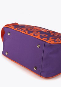 Bolsa de tela morada con un patrón naranja, forma rectangular, detalles naranjas y tachuelas metálicas en la base para estabilidad.