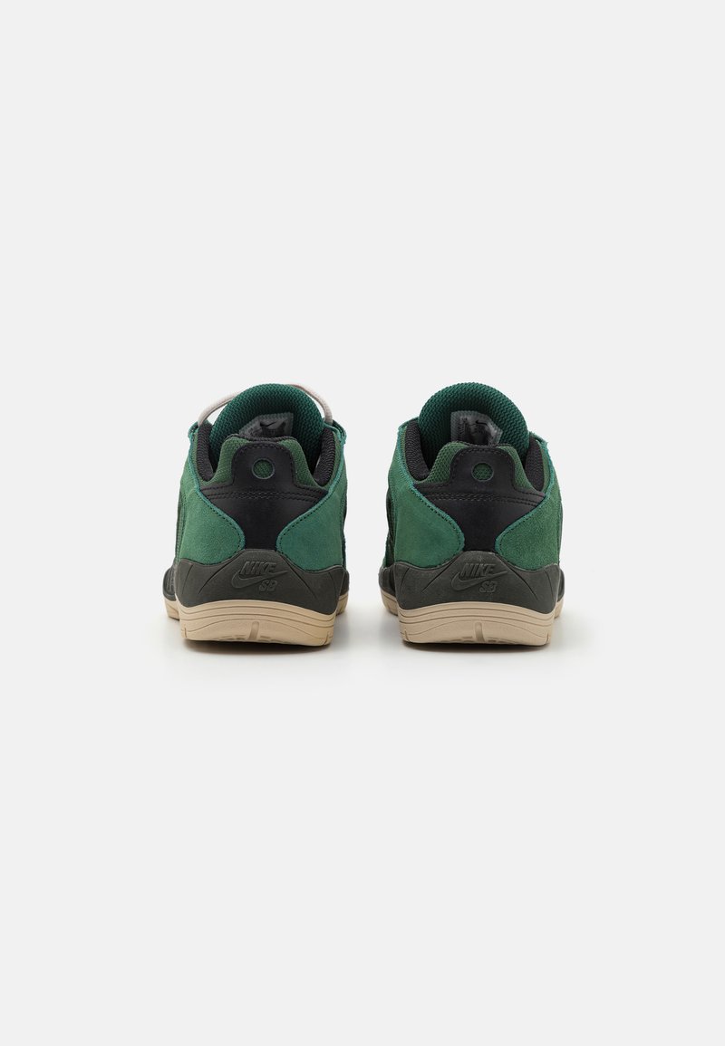 Zapatillas de ante verde y cuero negro con suela de goma, que cuentan con cuellos acolchados y un logo en el talón. Dos pares exhibidos desde atrás.