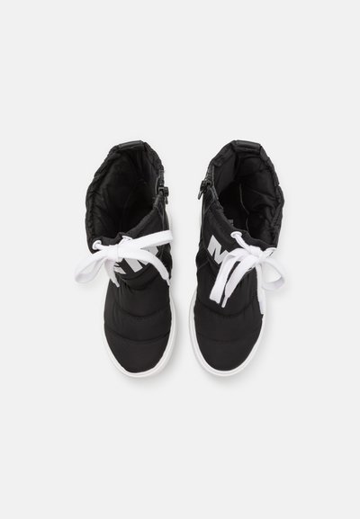 Sapatos pretos de cano alto com um upper de tecido acolchoado, atacadores brancos e uma sola de borracha branca. Possui um fecho éclair de lado e detalhes com o logótipo.