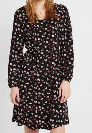 Zwarte jurk met lange mouwen en een vierkante halslijn; heeft een bloemenpatroon in roze, geel en rood; inclusief een strik in de taille.