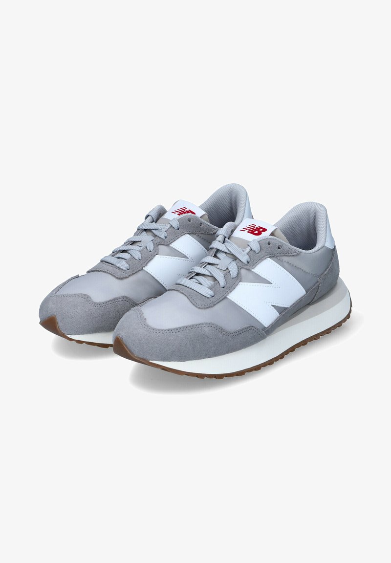 Zapatillas deportivas grises con materiales de ante y malla, acentos blancos y una suela de goma. Presentan una puntera redondeada y un diseño tradicional con cordones.
