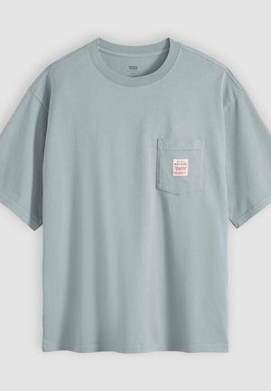 Lichtblauw katoenen T-shirt met korte mouwen en een borstzakje met een klein wit label met rode tekst.