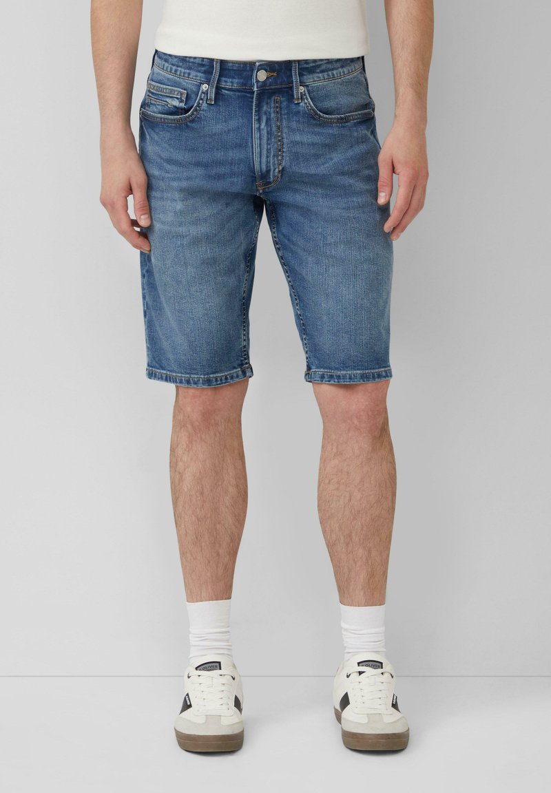 Lichte blauwe denimshorts met een klassiek vijf-pocket ontwerp, rechte pasvorm en omgeslagen zomen. Draagt met witte sneakers en sokken.