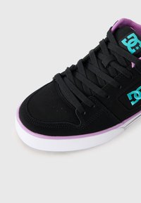 Zapatilla negra con logo turquesa, forro morado, cordones negros y suela blanca con ribete morado.