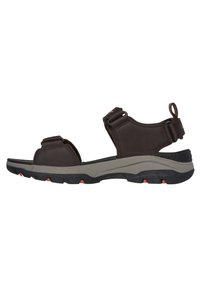 Sandal de color marrón con correas ajustables, plantilla acolchada y suela de goma negra texturizada con acentos naranjas y forma contorneada.