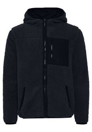 Crna dukserica s patentnim zatvaračem, koja ima prednji džep, bočne džepove i rebraste manžete. Mekana tekstura s mat finišom.