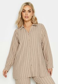 Camicia button-up a righe beige con colletto, maniche lunghe e vestibilità rilassata. Il tessuto presenta un aspetto testurizzato e intrecciato con strisce scure.