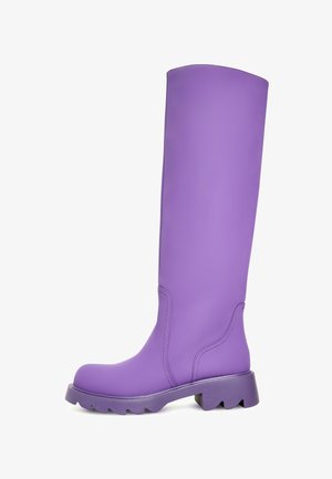 Lebhafte lila kniehohe Stiefel mit einer glatten, matten Oberfläche. Dicke, strukturierte Sohle mit breitem Absatz. Verfügt über subtile Nähdetails.