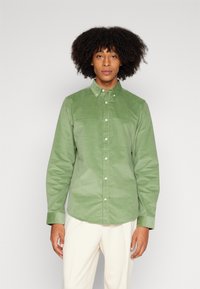 Cămașă din bumbac, cu nasturi, de culoare verde deschis, cu guler, mâneci lungi și nasturi albi. Textură netedă, croială ajustată și fără modele vizibile.