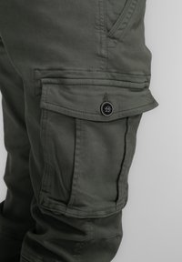 Cargo-broek in donker olijfgroen, met een zijzak met een knoopsluiting, recht model en zachte, gestructureerde stof.