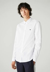 Witte button-up shirt gemaakt van katoen met een klassieke kraag. Bevat een groen geborduurd logo op de linkerborst en lange mouwen.