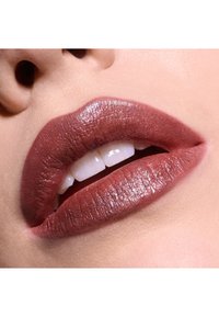 Matte mauve læbestift på fyldige læber, der fremviser en glat tekstur med subtil glans. Hvide tænder er let synlige.