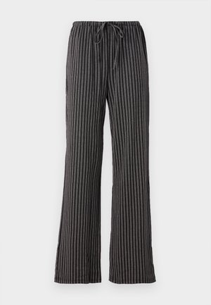 Pantalons de pyjama rayés noir et blanc, avec une taille à cordon, des jambes larges et un tissu doux et texturé avec des lignes verticales.