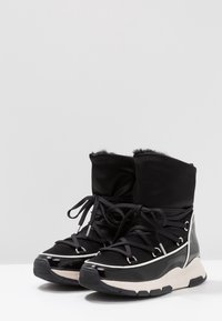 Czarne zimowe buty z nylonową cholewką, ozdobione sztucznym futerkiem oraz błyszczącą czarną osłoną palców. Posiadają srebrne elementy metalowe, sznurowadła i grubą podeszwę.