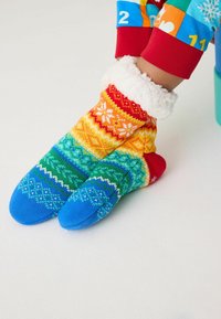 Bunte Stricksocken mit einem Muster aus Grün, Gelb, Rot und Blau, einem flauschigen weißen Bund und Schneeflockendesigns.