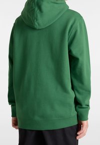 Groene hoodie met een ruime capuchon, lange mouwen en een relaxte pasvorm. Gemaakt van zachte stof met een gladde textuur. Eenvoudig ontwerp, geen patronen.