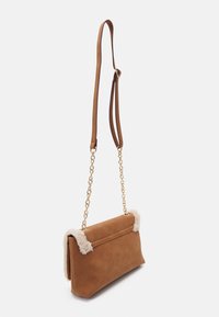 Braune Wildleder-Schultertasche mit einem plüschigen cremefarbenen Besatz, goldener Kette und Ledertragegurt, die eine rechteckige Form und glatte Oberfläche aufweist.