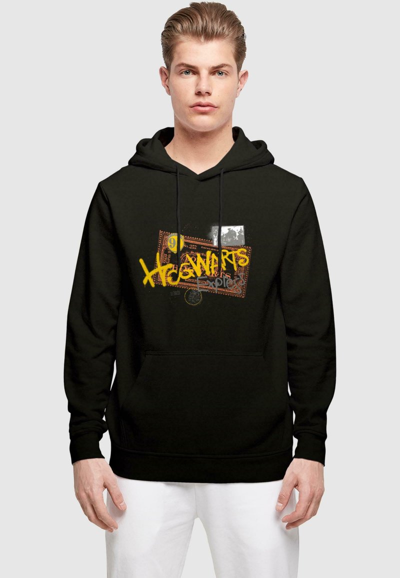 Čierna mikina s kapucňou a prednou vreckom, so grafickým dizajnom, ktorý obsahuje "Hogwarts" v žltej farbe na textúrovanom pozadí so znakmi.