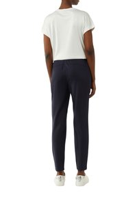 Witte t-shirt met korte mouwen, gecombineerd met marineblauwe slim-fit broek en witte sneakers. Soepele stof, aansluitend ontwerp en elastische tailleband.