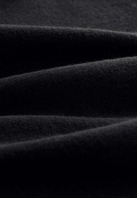 Tissu noir texturé avec des vagues douces et lisses, présentant un motif de maille fine. Le matériau semble léger et légèrement duveteux.