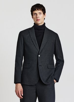 Dunkelgrauer taillierter Blazer mit einreihiger Knopfleiste und zwei Fronttaschen, getragen über einem schwarzen Rollkragenpullover und aus einem strukturierten Stoff gefertigt.